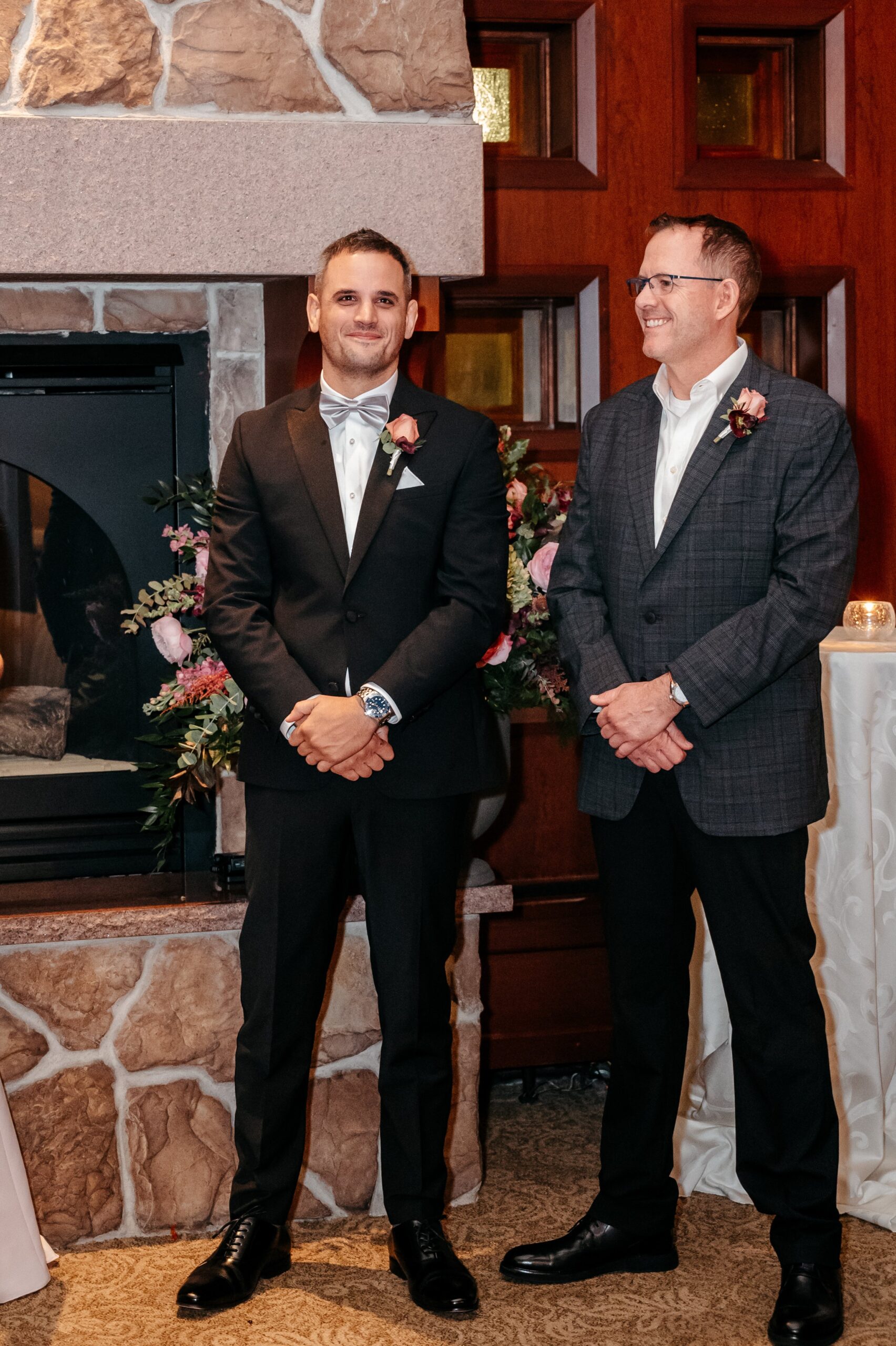 Groom waiting by fireplace with groomsman during Cafe Escadrille wedding ceremony, classic formal dress code attire
