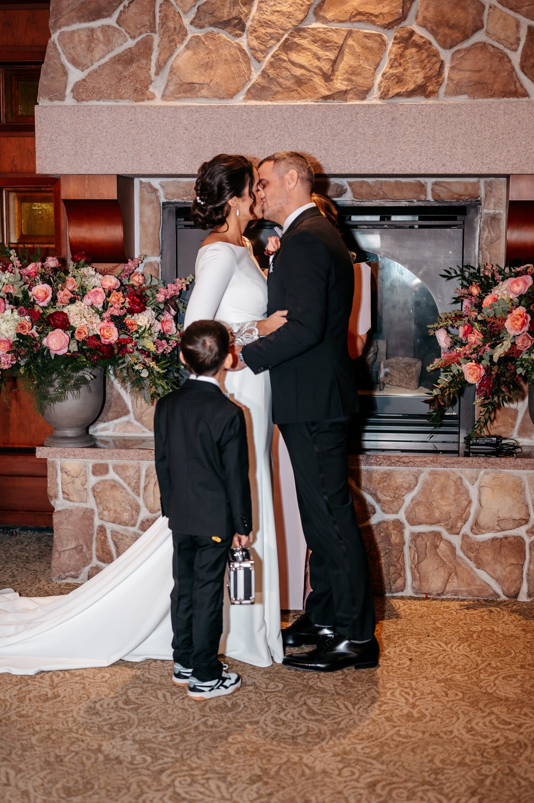 Bride and groom sharing first kiss at Cafe Escadrille wedding in Burlington, romantic ceremony moment by fireplace