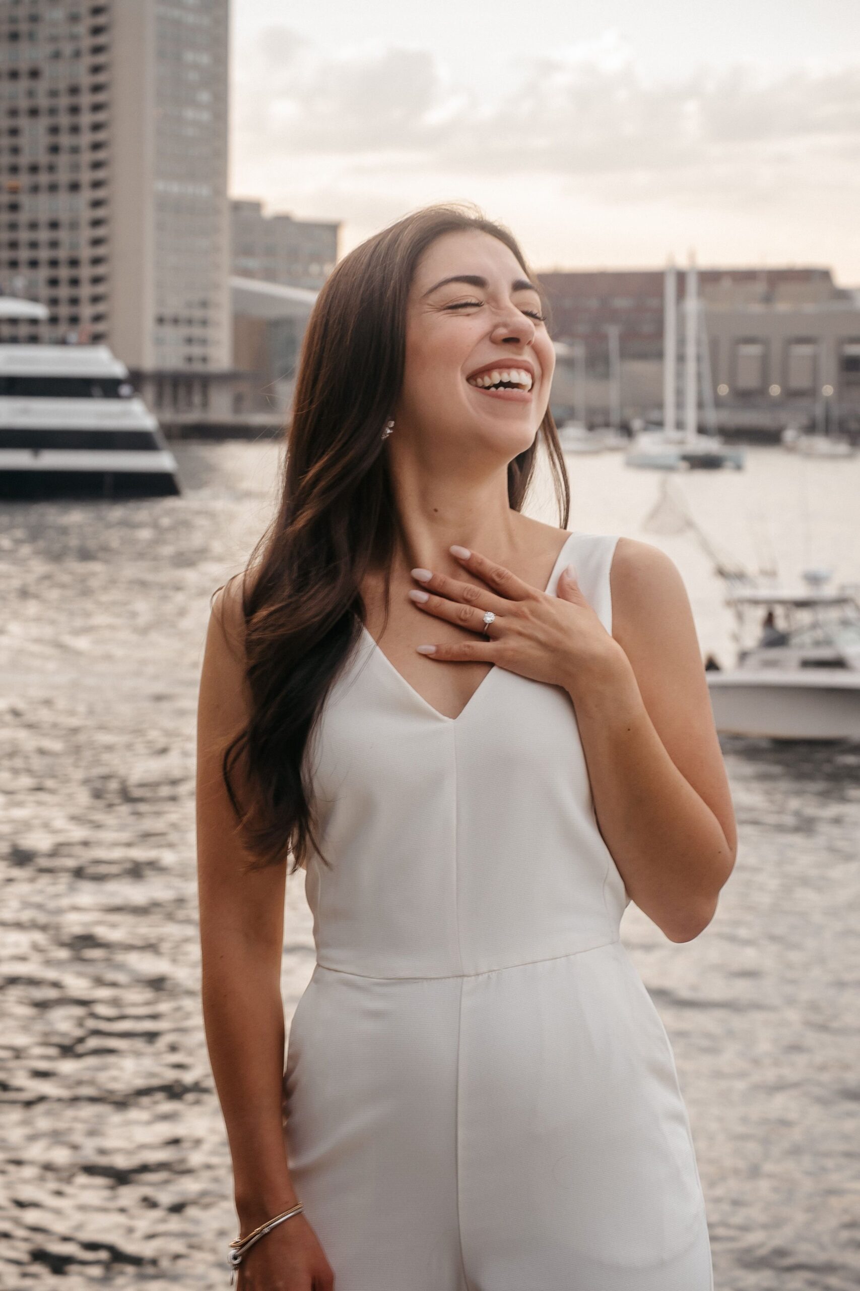 Bride-to-be laughing during Fan Pier Park Boston engagement session, joyful waterfront portrait at sunset