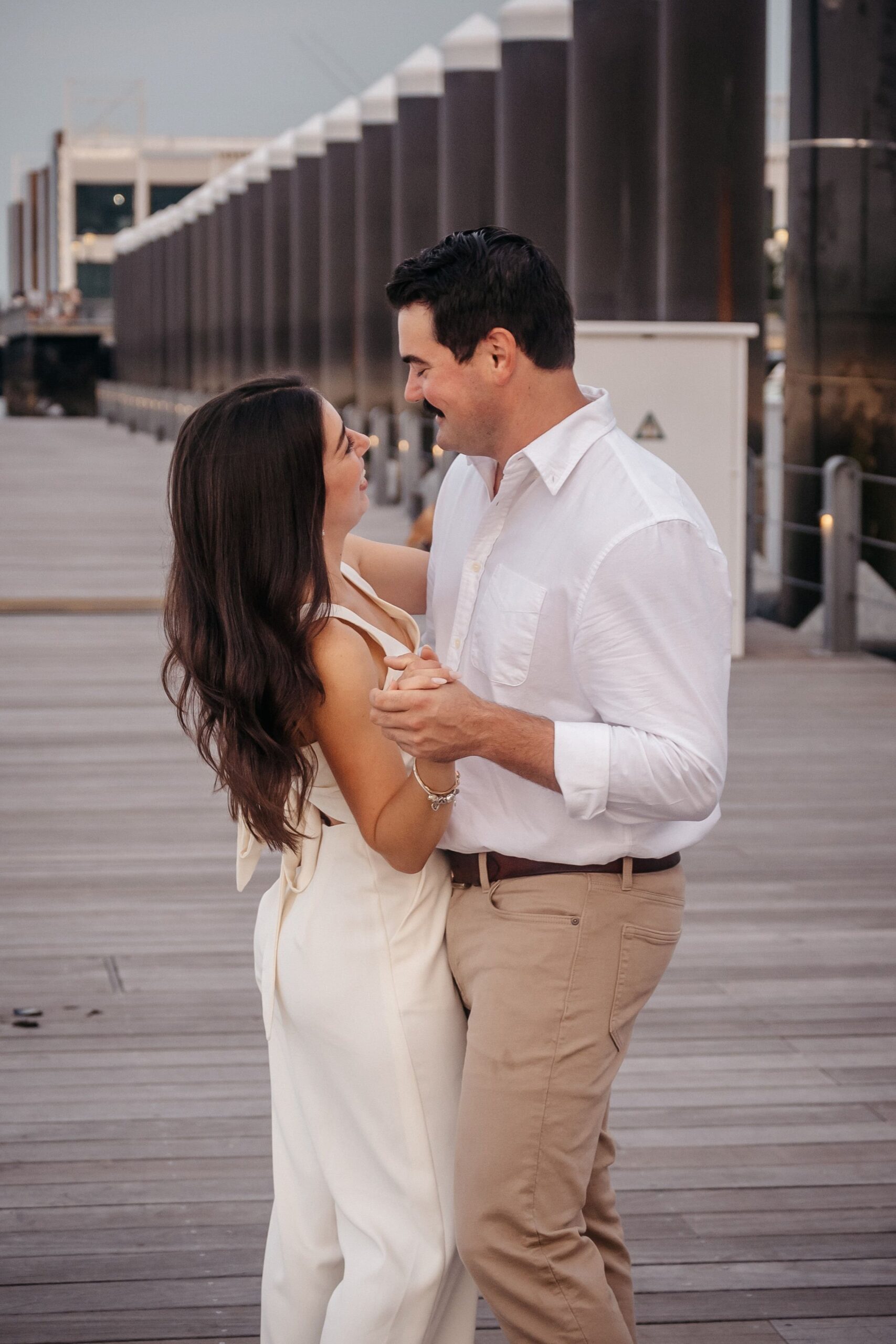 Couple dancing together at Fan Pier Park during engagement session, playful waterfront moment in Boston