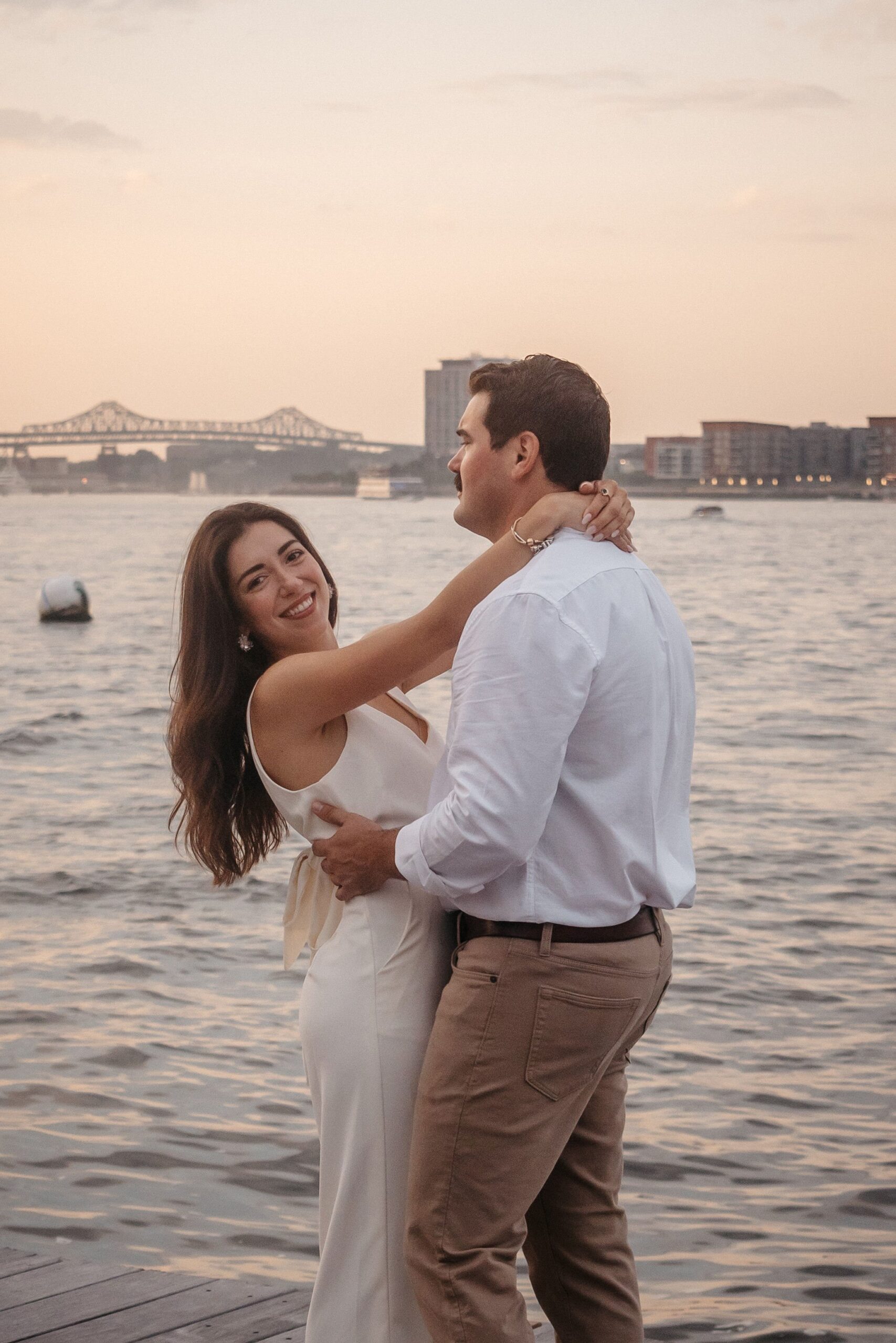Smiling bride-to-be during Fan Pier Park engagement session, romantic waterfront portrait at sunset in Boston