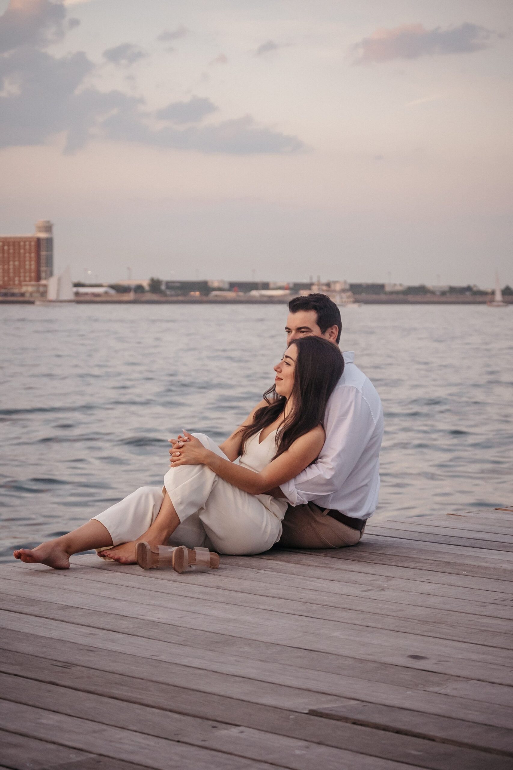 Romantic waterfront moment during Fan Pier Park engagement session, couple relaxing together on the dock at sunset