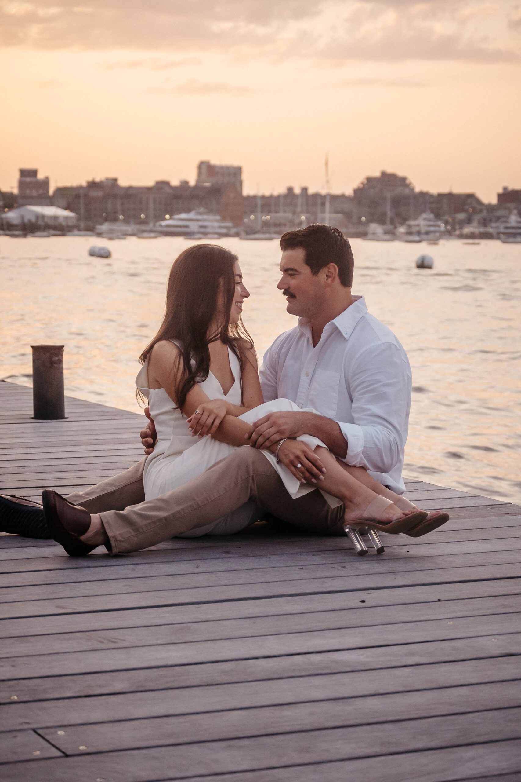 Couple embracing on the dock at Fan Pier Park during golden sunset engagement session in Boston