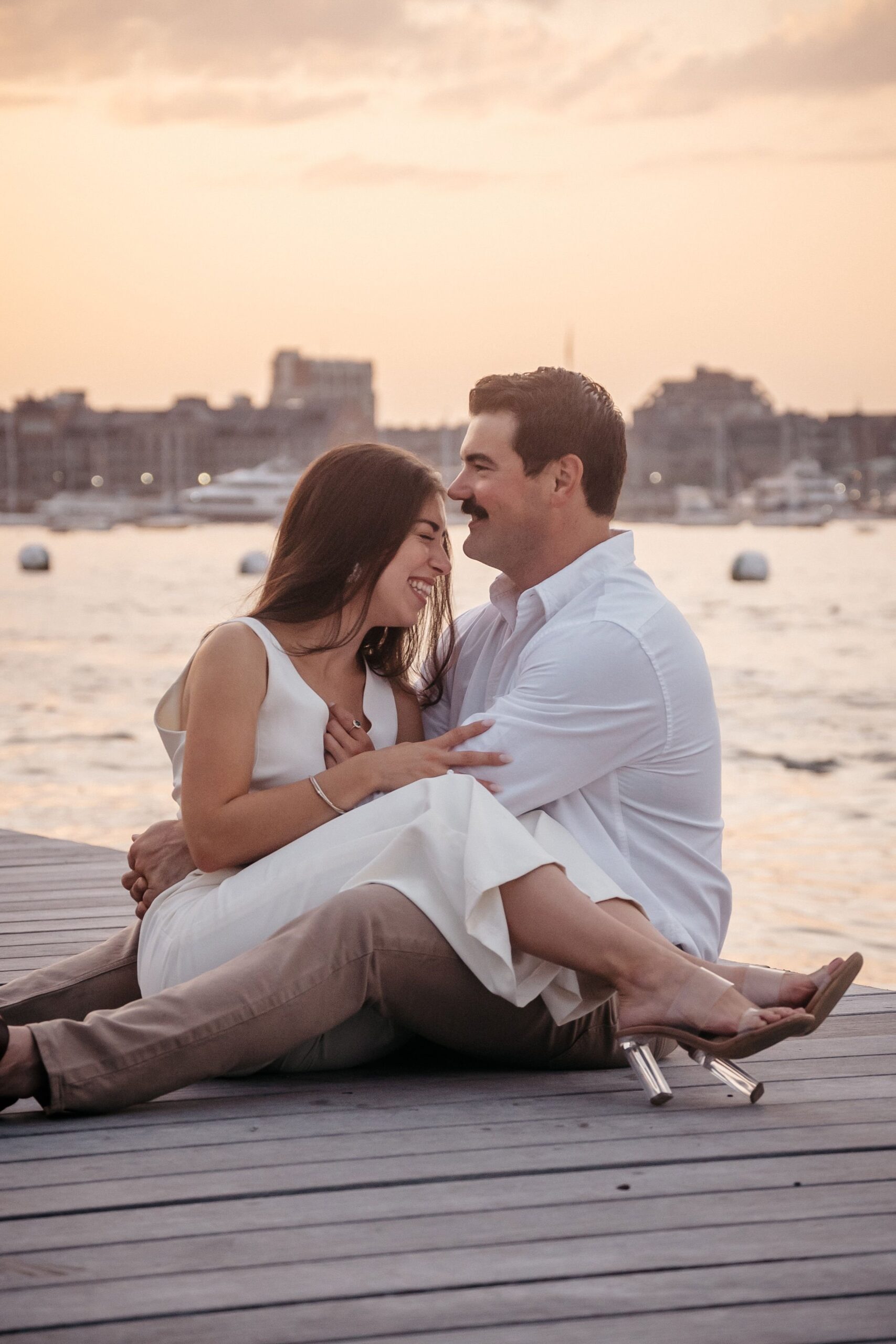 Playful candid moment during Fan Pier Park engagement session, couple laughing together at sunset by the water
