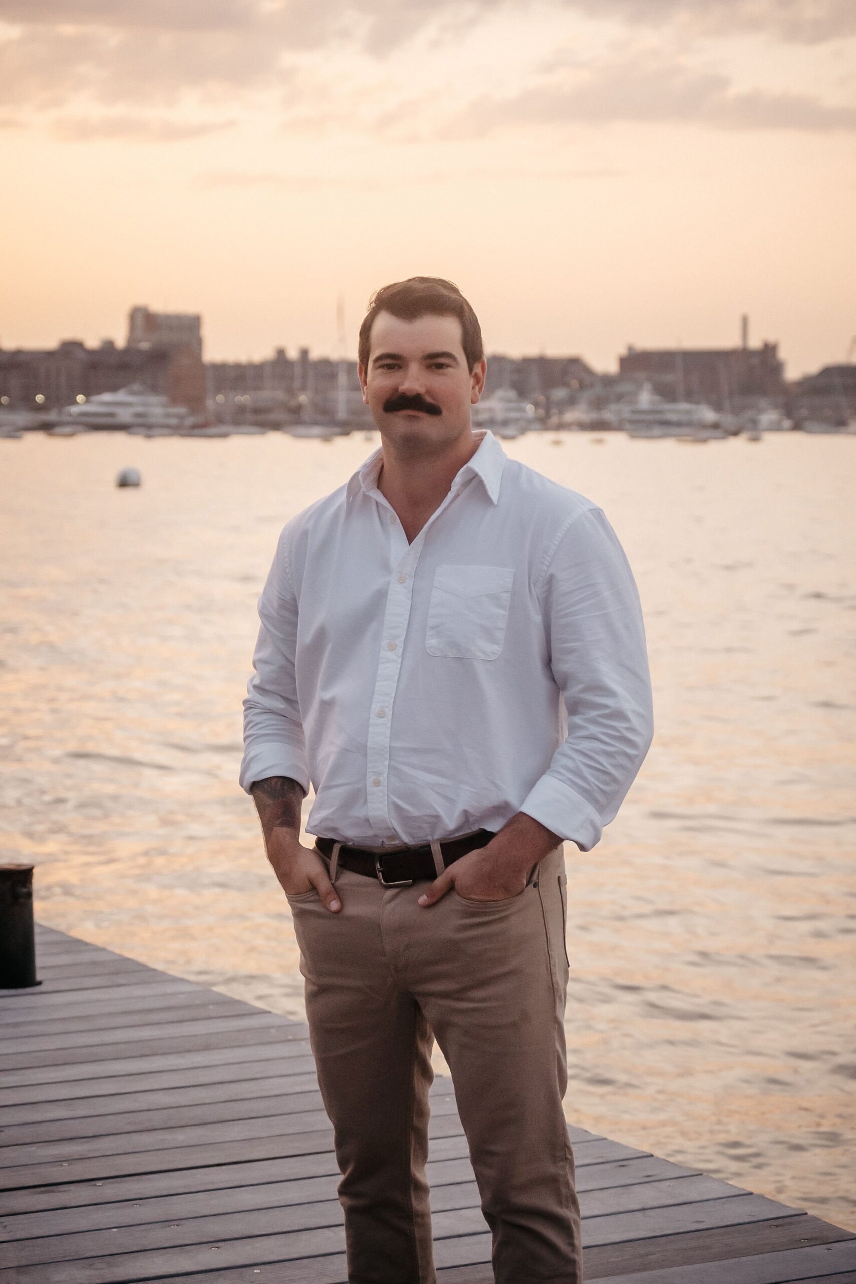 Groom portrait at Fan Pier Park Boston during engagement session, waterfront sunset with harbor views