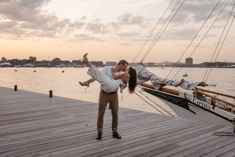 Couple kissing during Fan Pier Park Boston engagement session, dramatic sunset portrait by the harbor