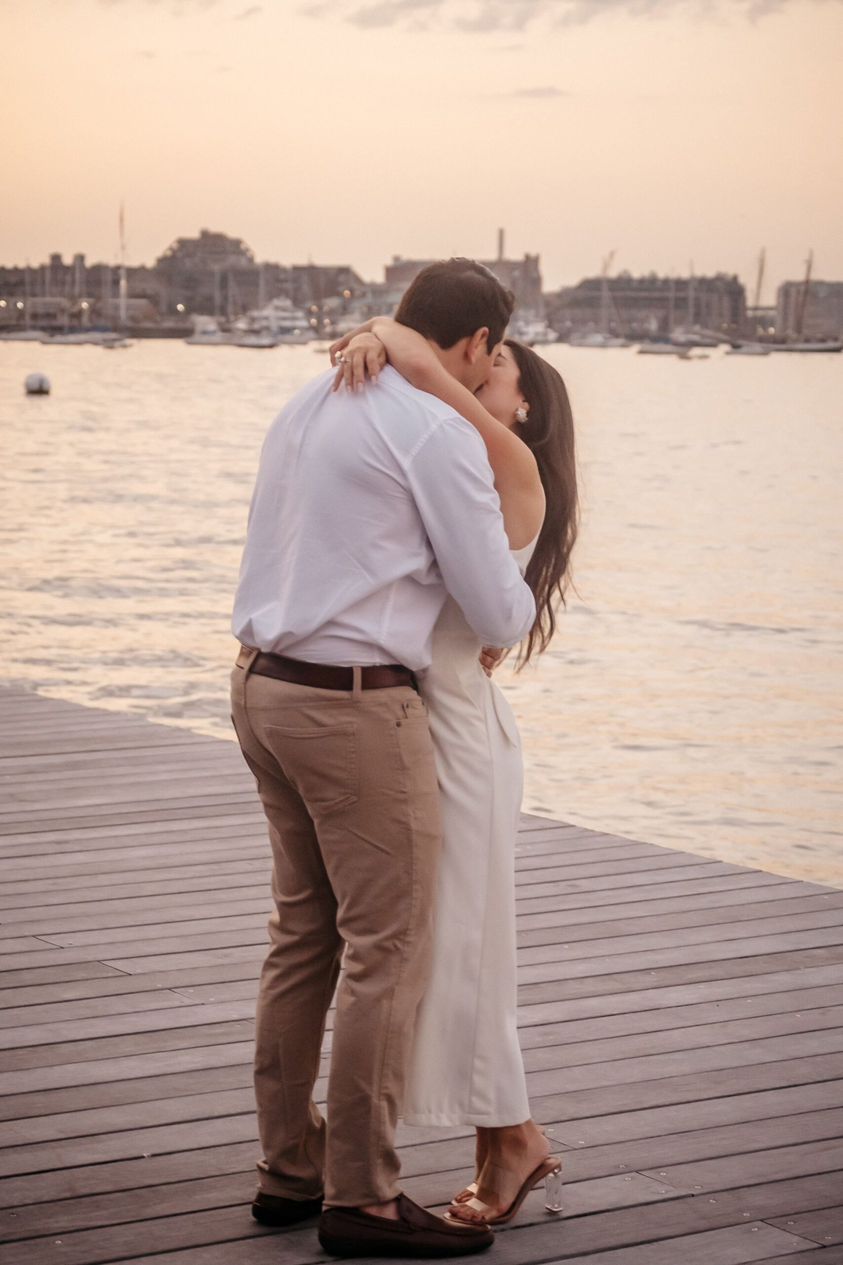 Romantic kiss during Fan Pier Park engagement session, intimate waterfront moment with Boston harbor at sunset