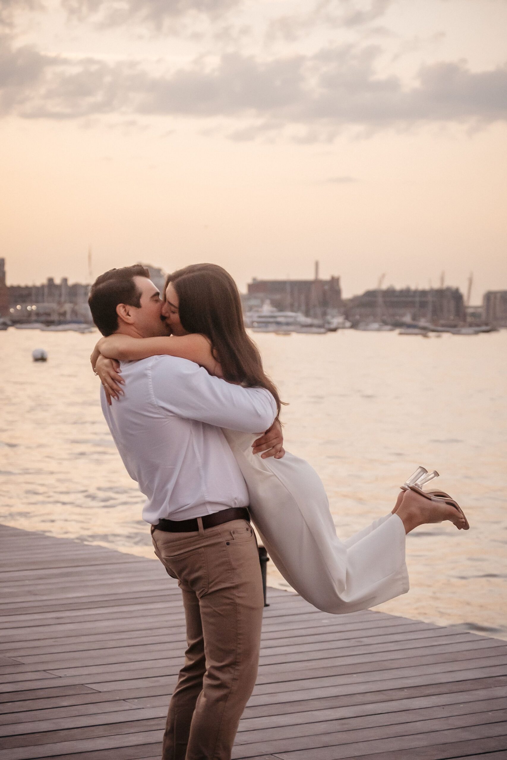 Couple dipping into a kiss at Fan Pier Park Boston, dramatic sunset engagement session on the waterfront pier