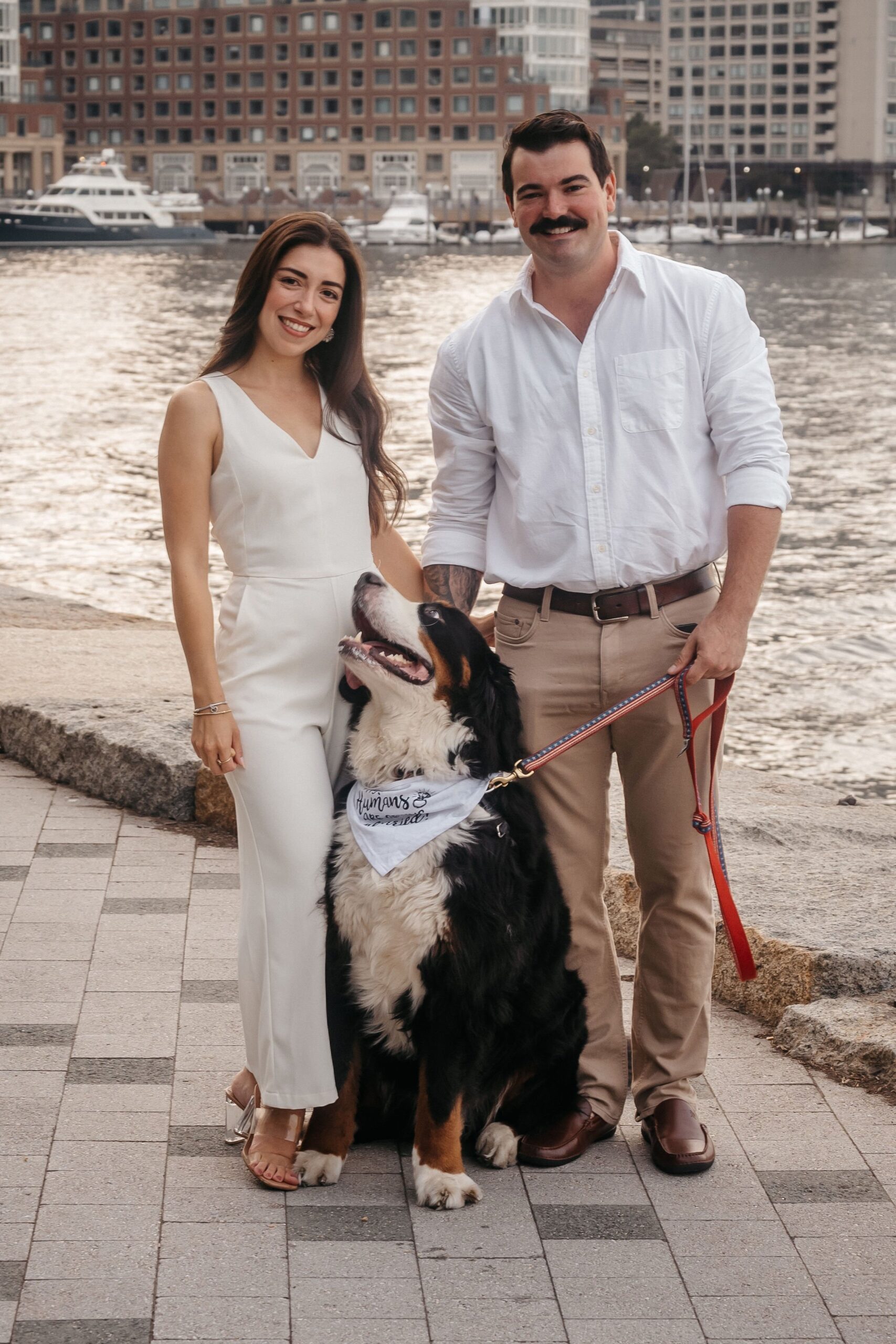 Engaged couple with their dog at Fan Pier Park Boston, relaxed waterfront portrait during golden hour sunset