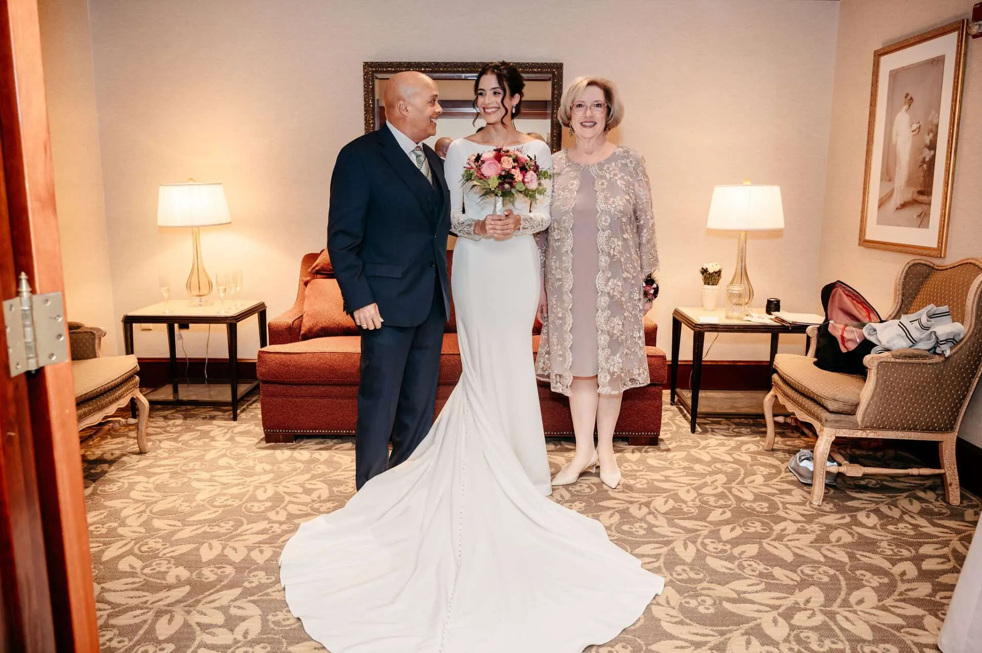 Bride with her parents in a hotel sitting room before the ceremony