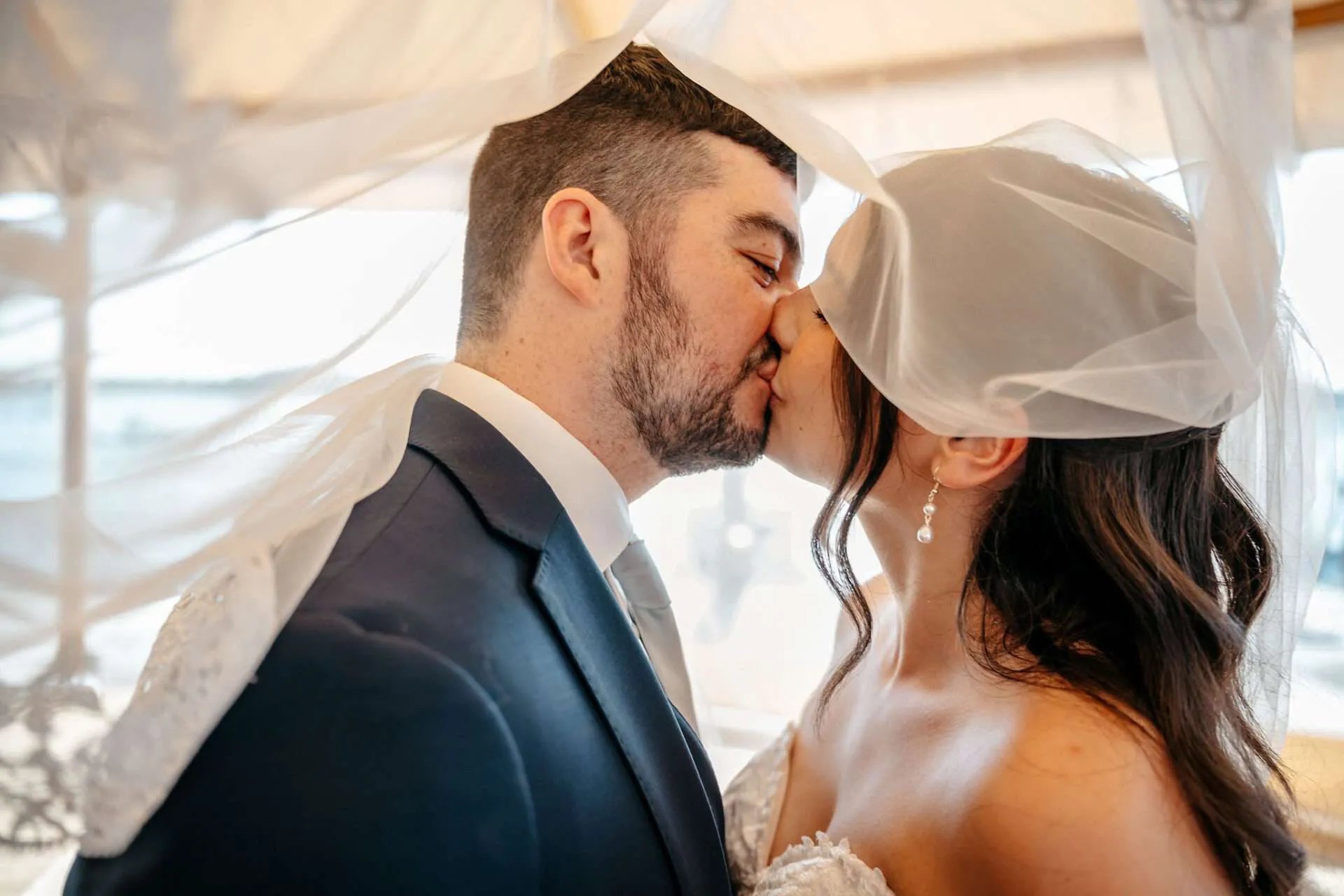 Bride and Groom kiss under the veil at one of the best burlington wedding locations