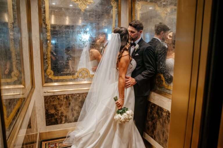 Bride and groom kissing in an ornate gold mirrored elevator