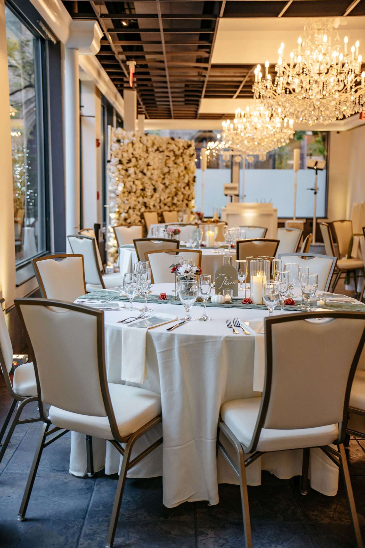 A reception area in seaport village wedding venues with chandeliers, white chairs, and white flowers