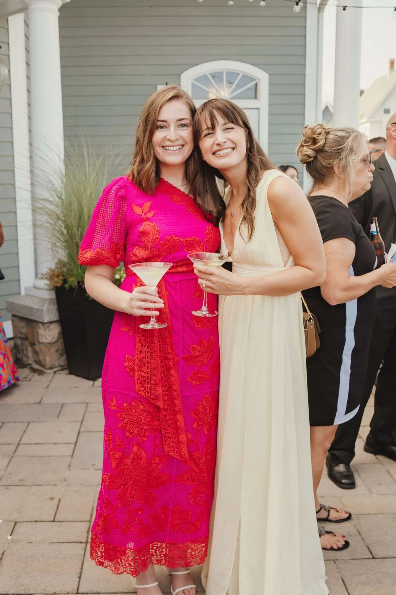 Two women holding martini glasses smile at a wedding in a Boston Seaport wedding venue