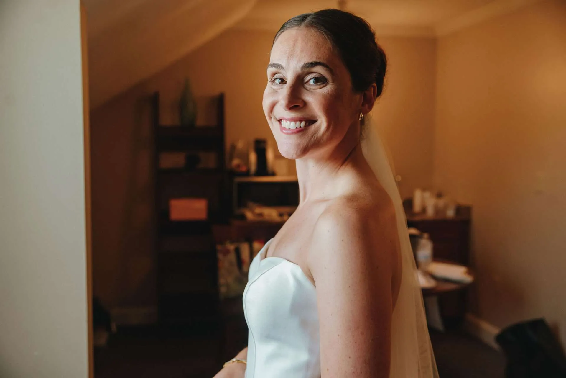 A bride in her gown smiles while getting ready in her Seaport village wedding venues