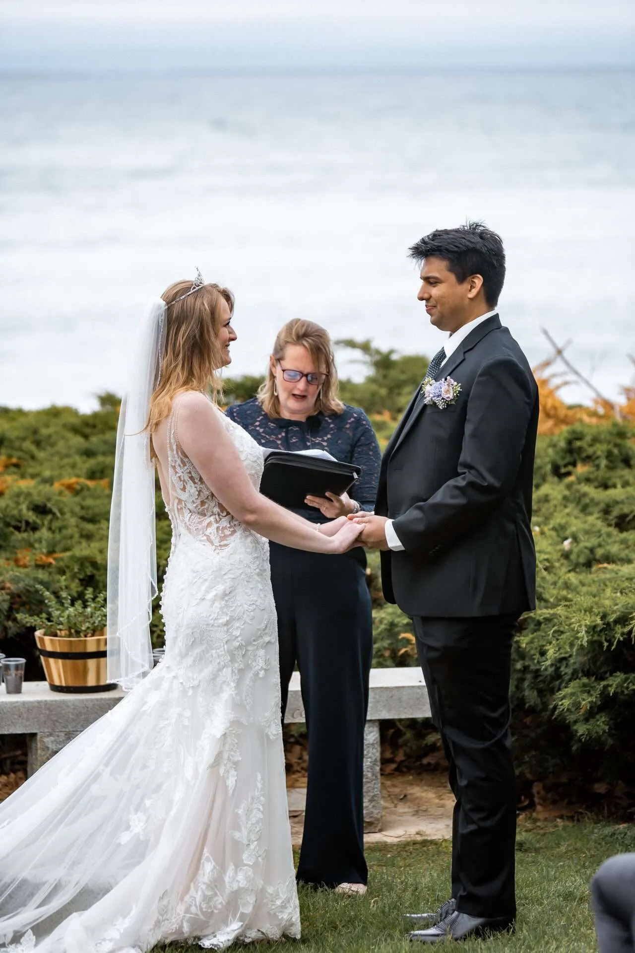 A bride and groom hold hands while saying their vows at their Seaport village wedding venues