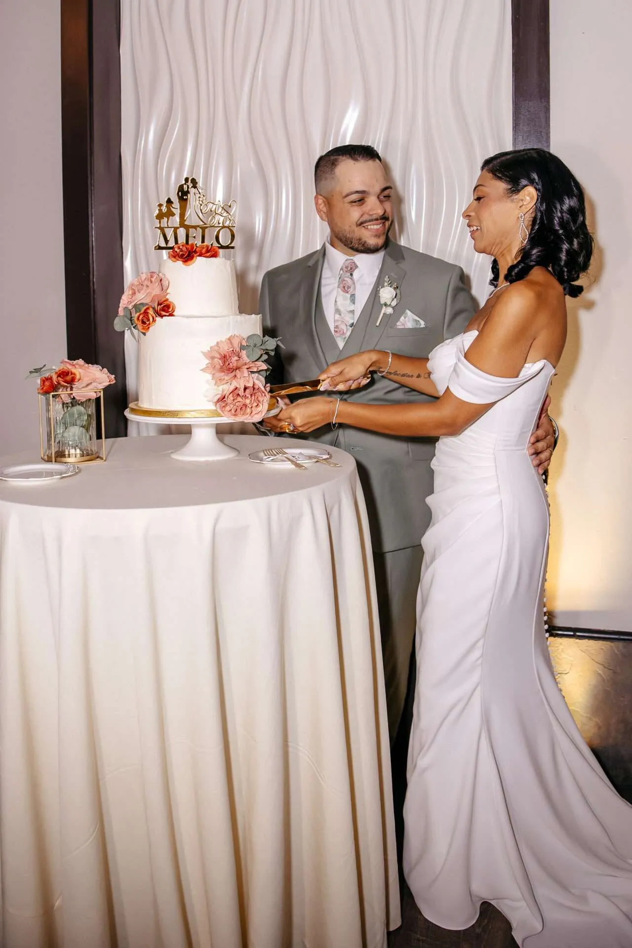 A bride and groom cut their wedding cake with red and pink flowers at Seaport village wedding venues