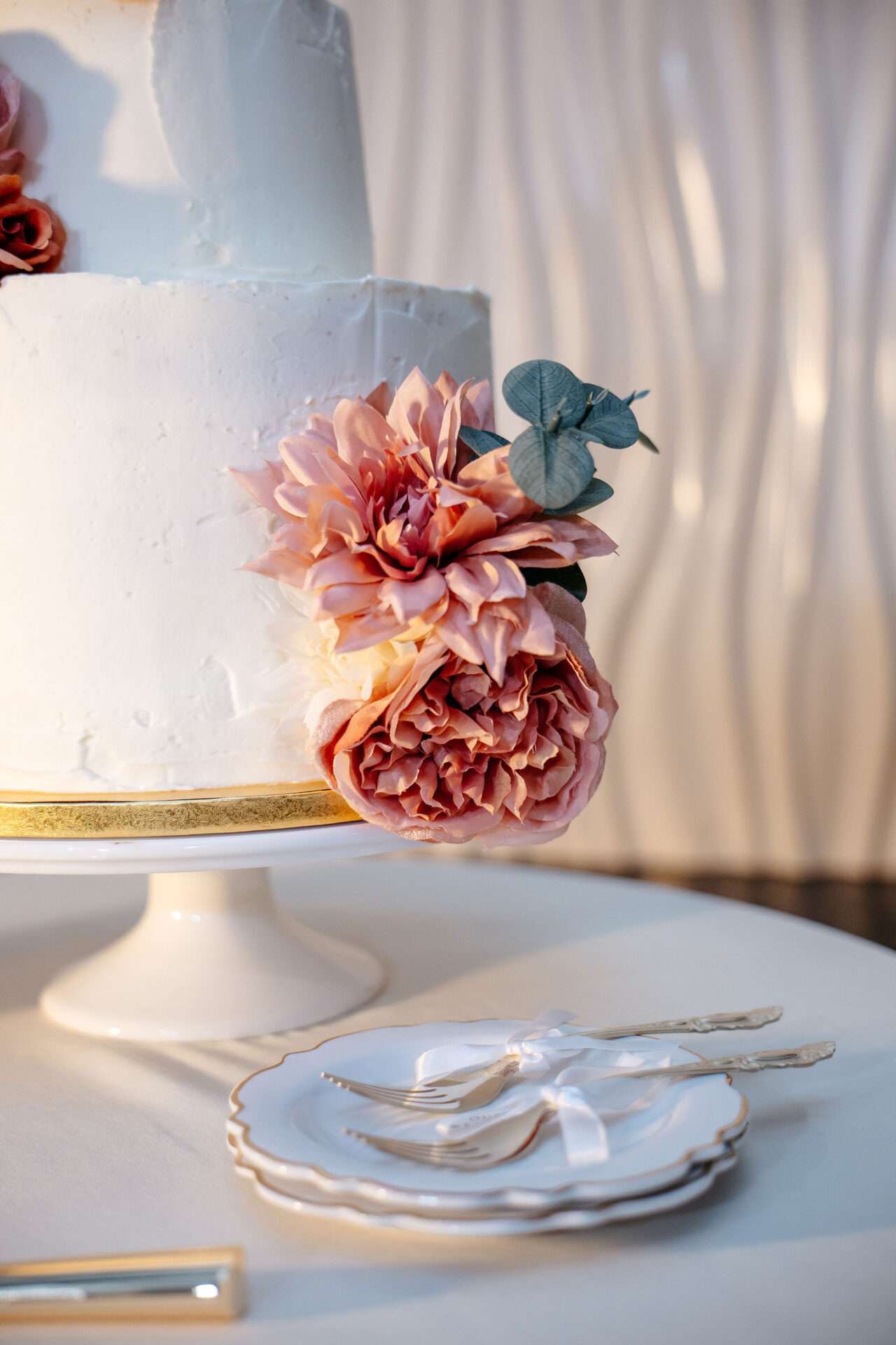 A white wedding cake with pink flowers on displat at a Boston Seaport wedding venue