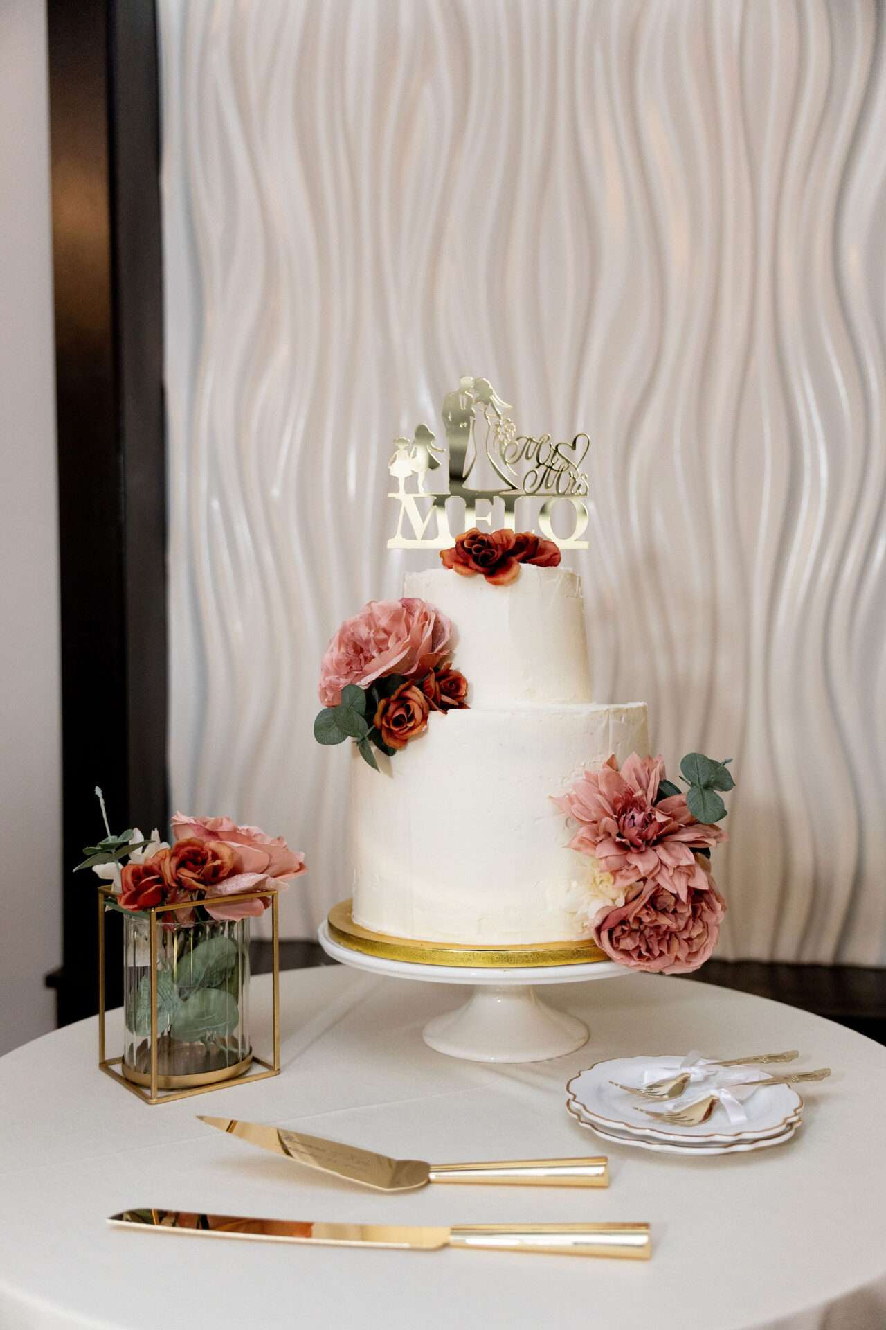A two-tier white wedding cake with pink and red flowers on display at Seaport Boston wedding venues