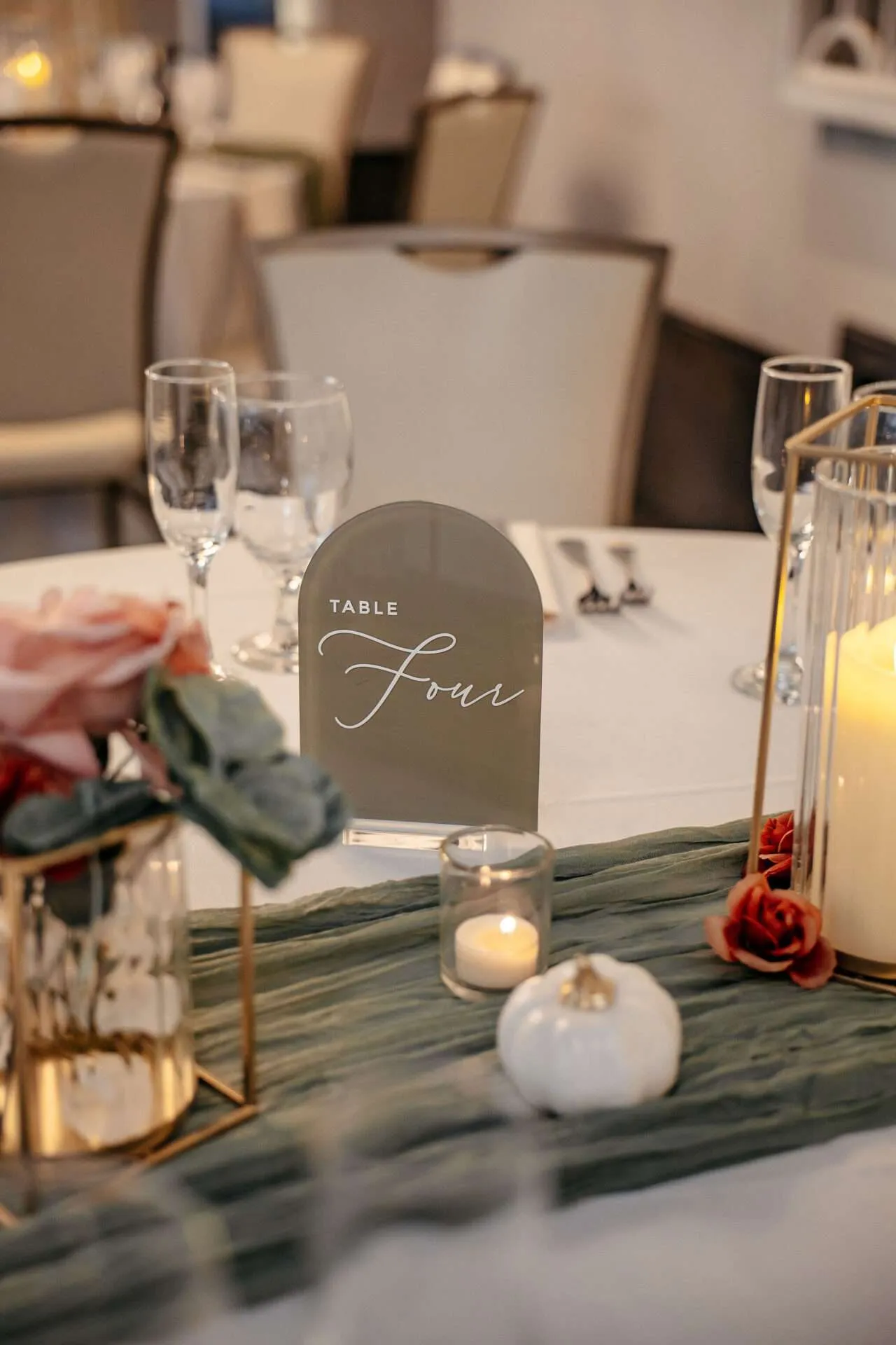 A table decorated with candles, flowers, glasses, and a green table runner at a Seaport wedding venue