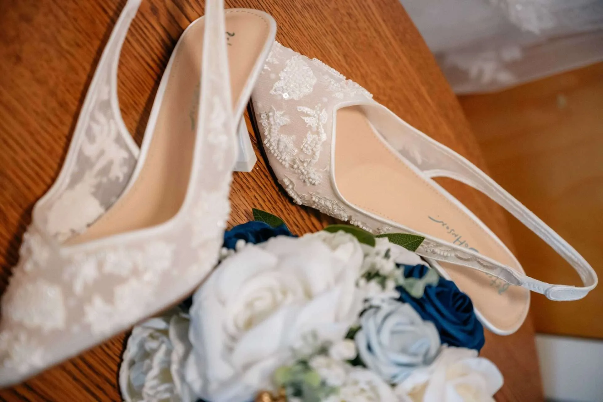 brides wedding shoes on table alongside flowers at one of the most unique wedding venues in boston
