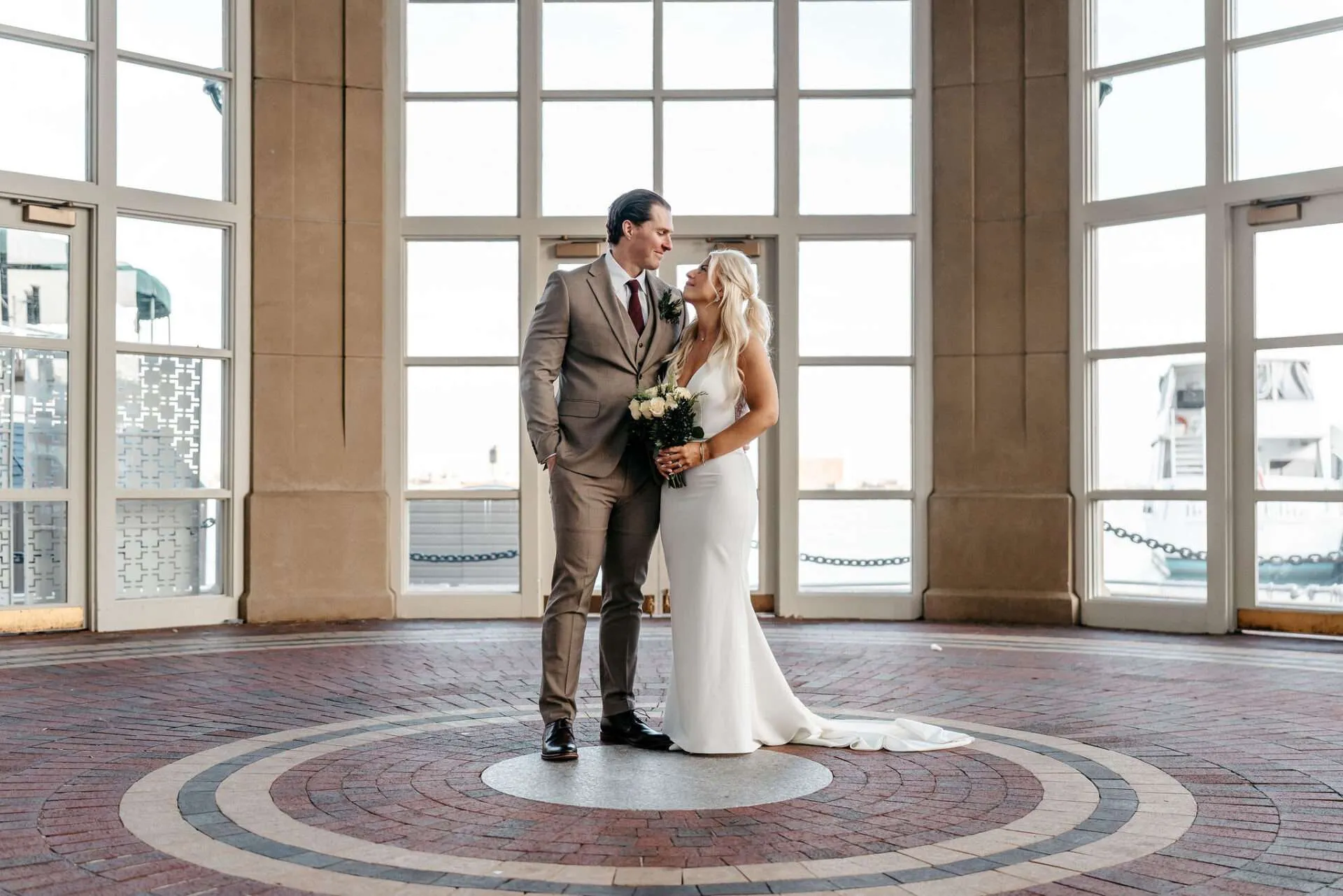 Bride and groom getting married at city hall Boston look at each other longingly while standing in the lobby of the City Hall building 