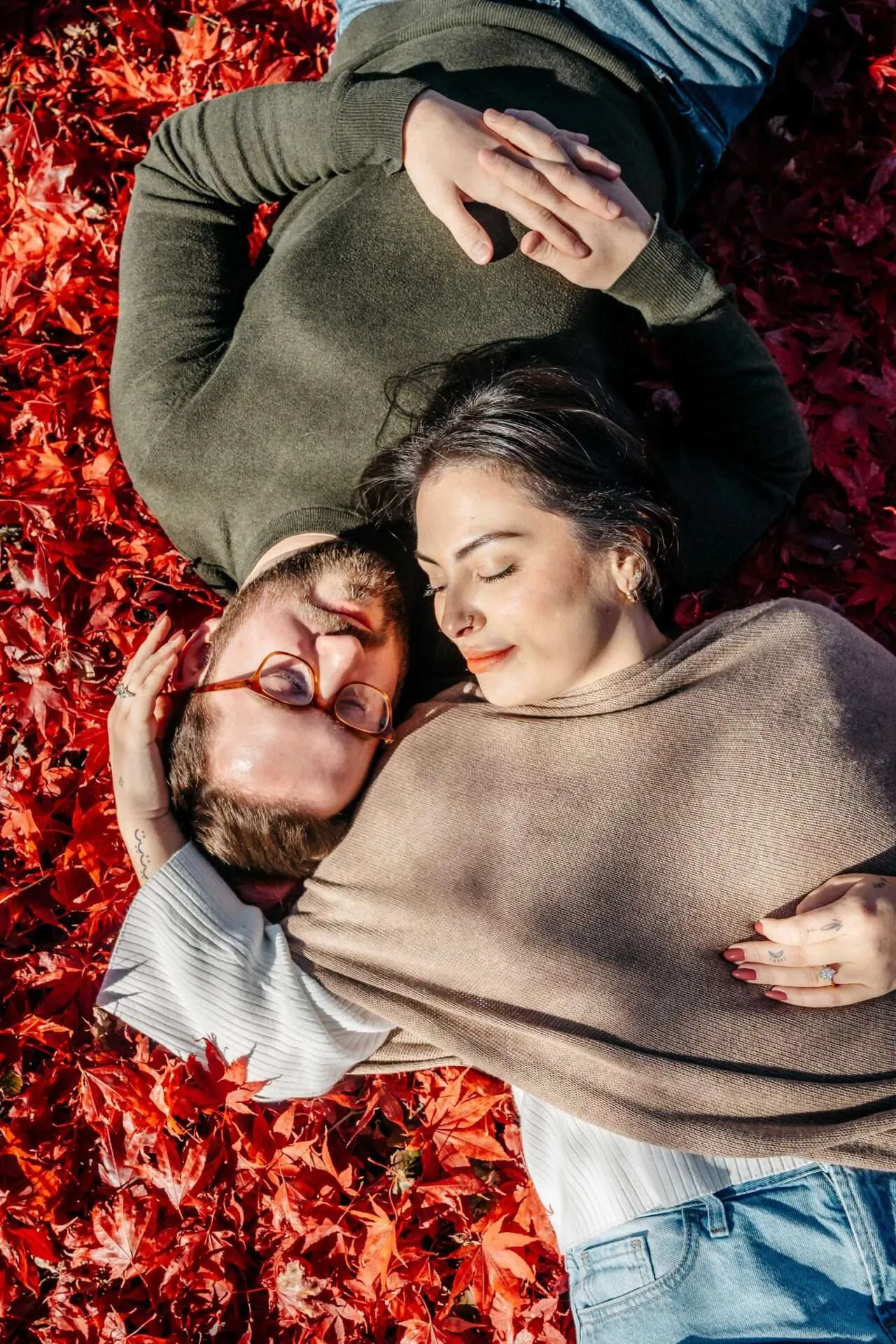 couple on ground looking at one another surrounded by leaves