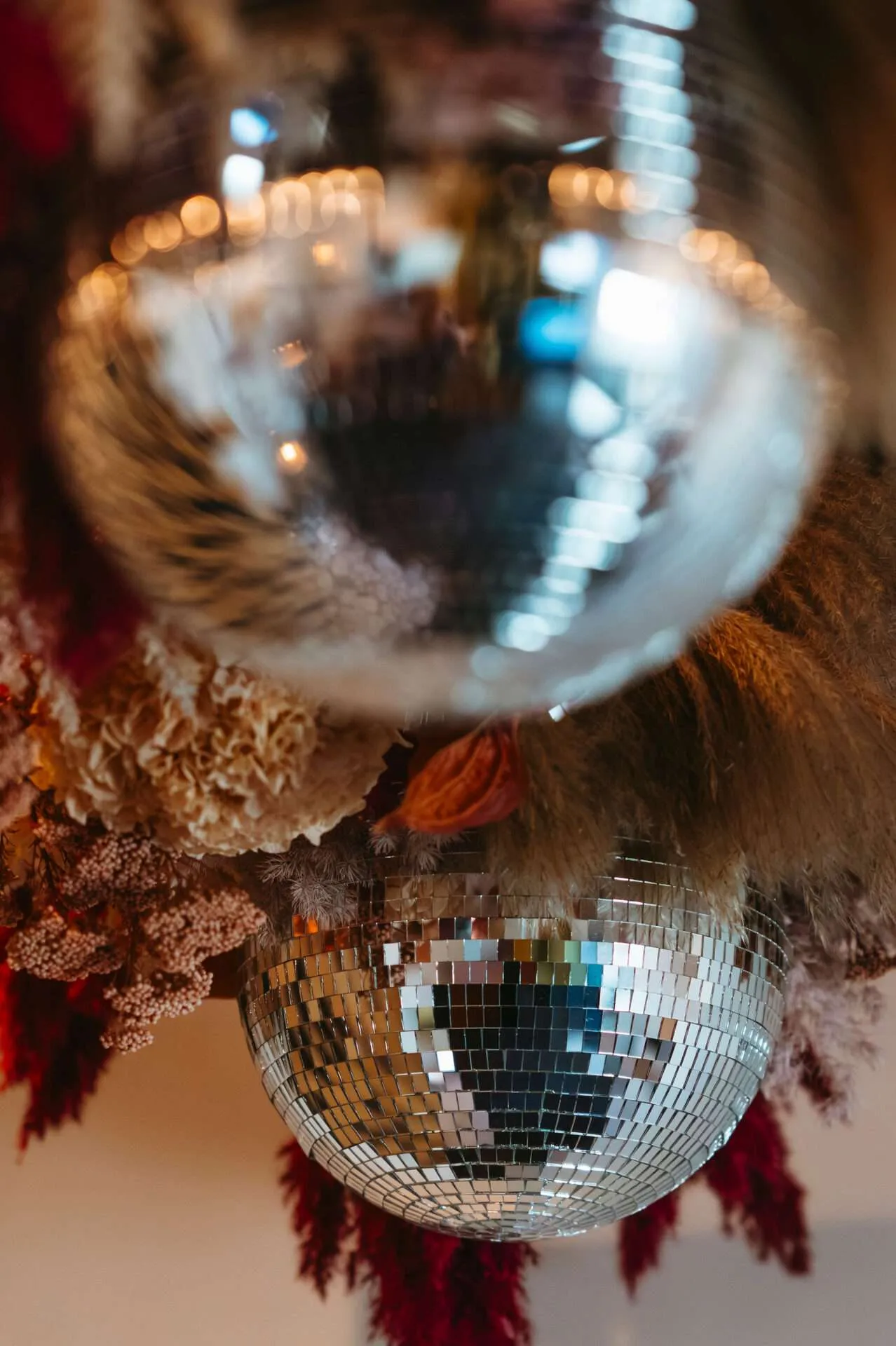 Disco balls and pink and burgundy flowers hang from a ceiling in small wedding venues in boston ma