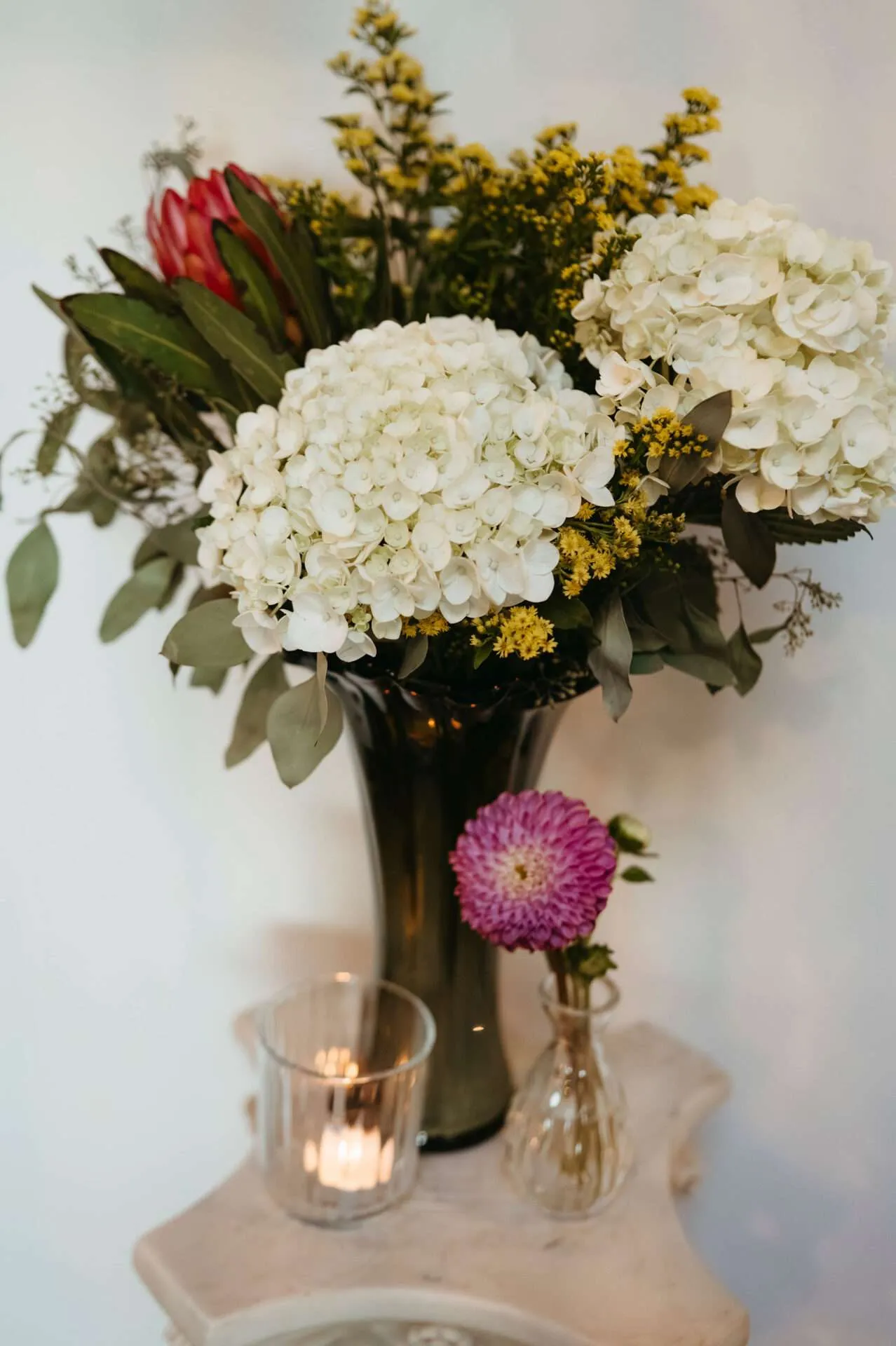 Boston wedding florists arrange a beautiful bouquet of white carnations and greenery for centerpieces at a wedding 

