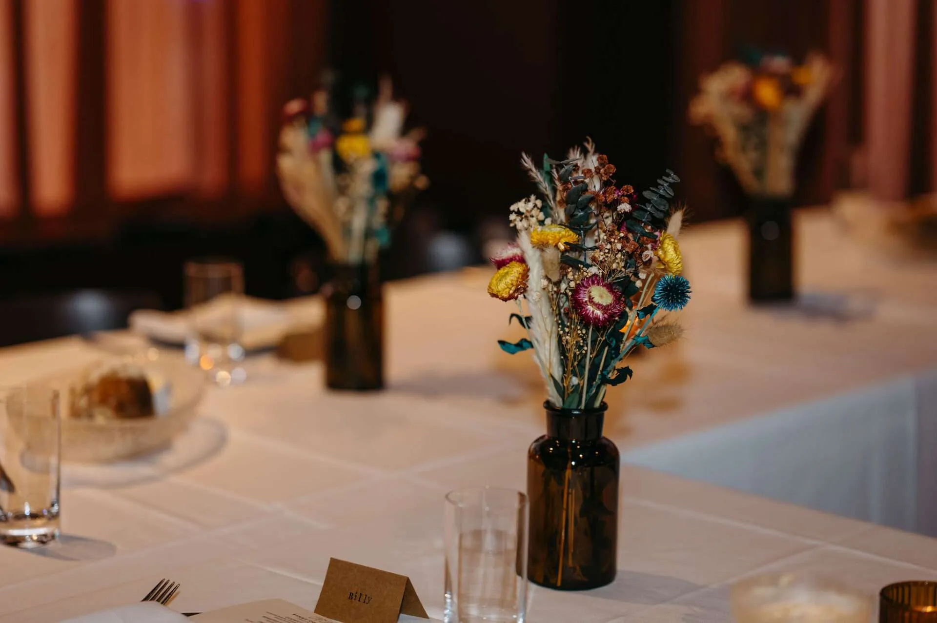 Two beautiful flower arrangements by a Boston wedding florist sit on a table at a reception
