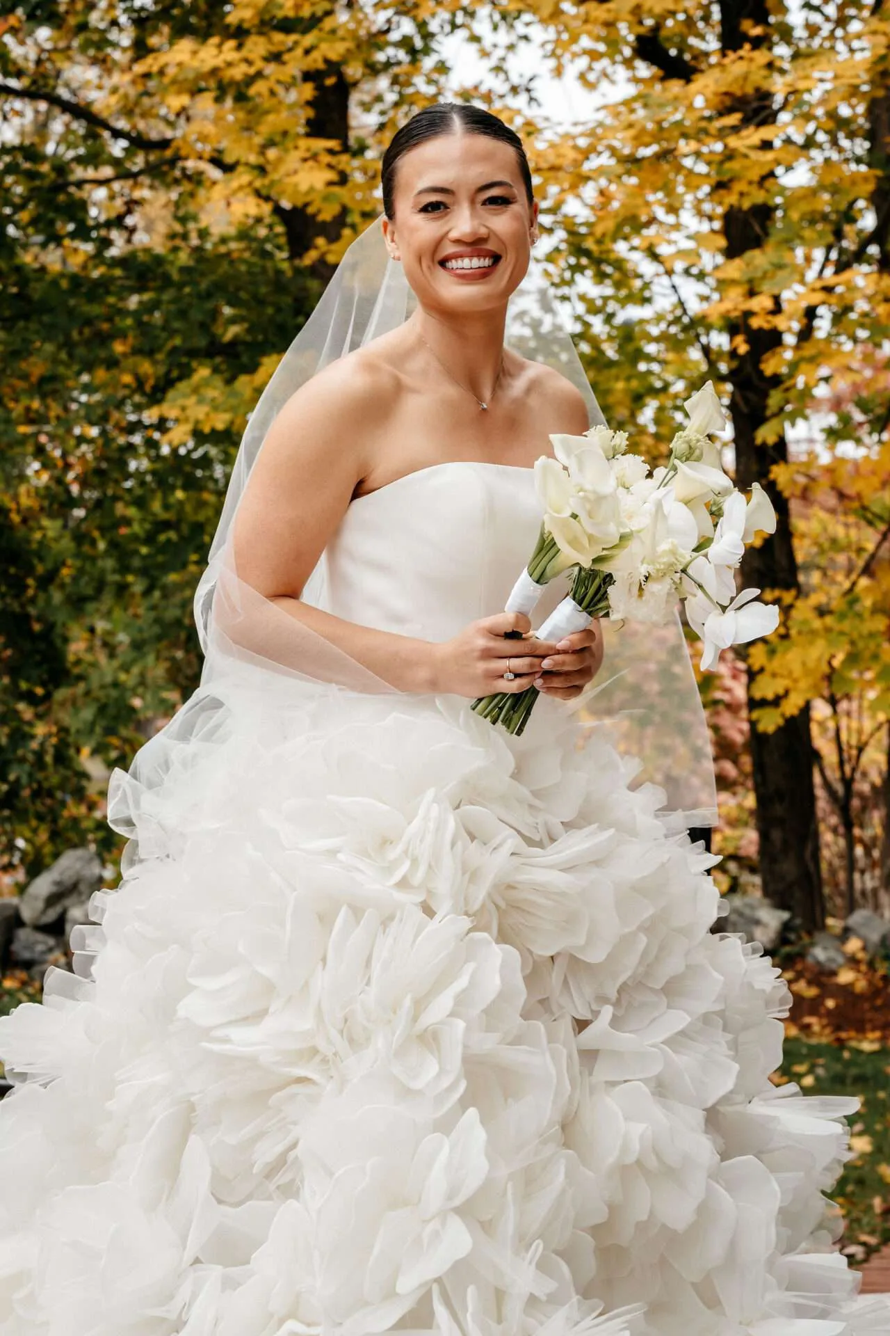 A bride holds a white bouquet of flowers designed by wedding florists in boston
