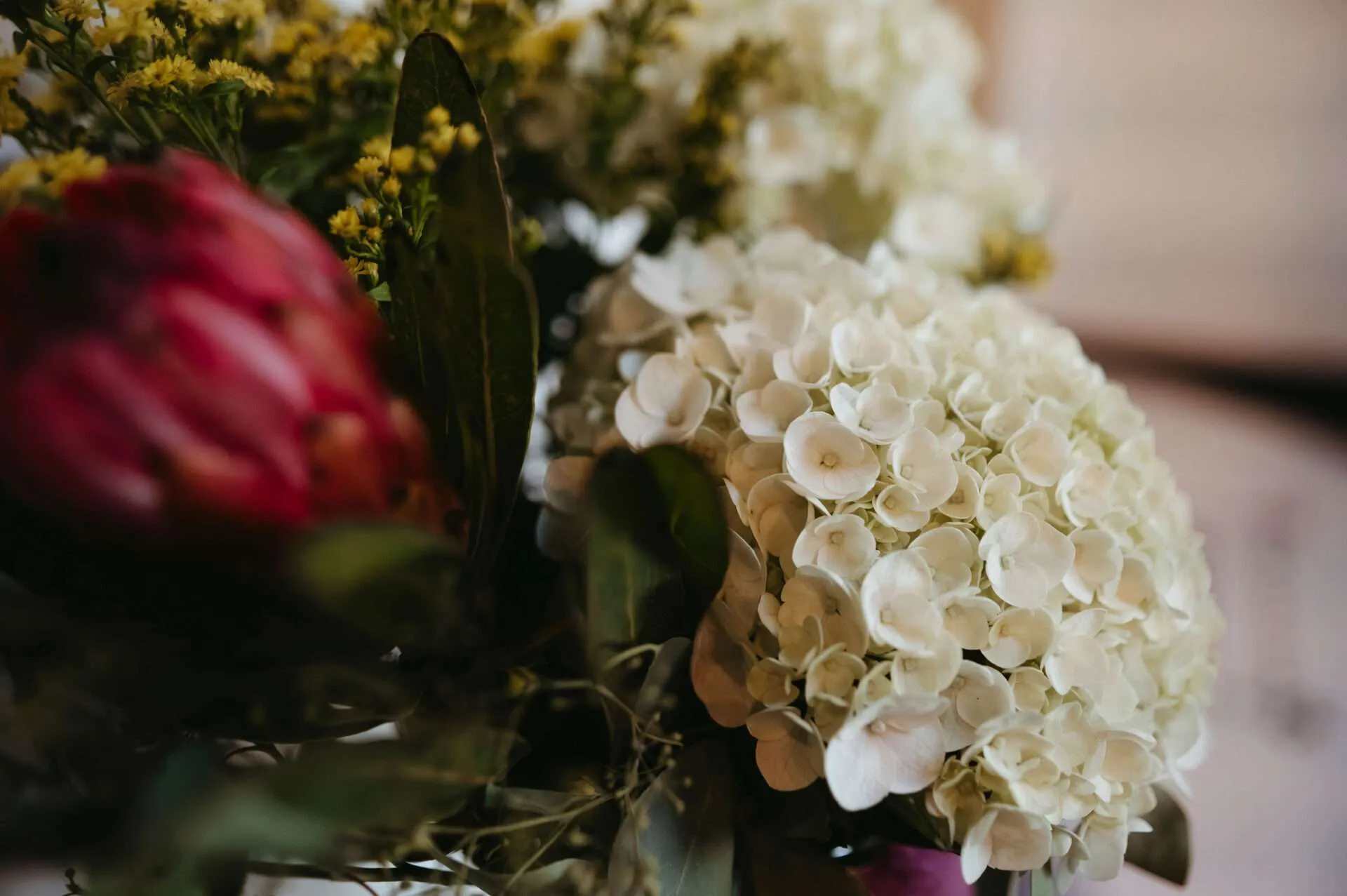 White and red flowers surrounded with greenery are arranged in a vase for a reception by a wedding florist in boston
