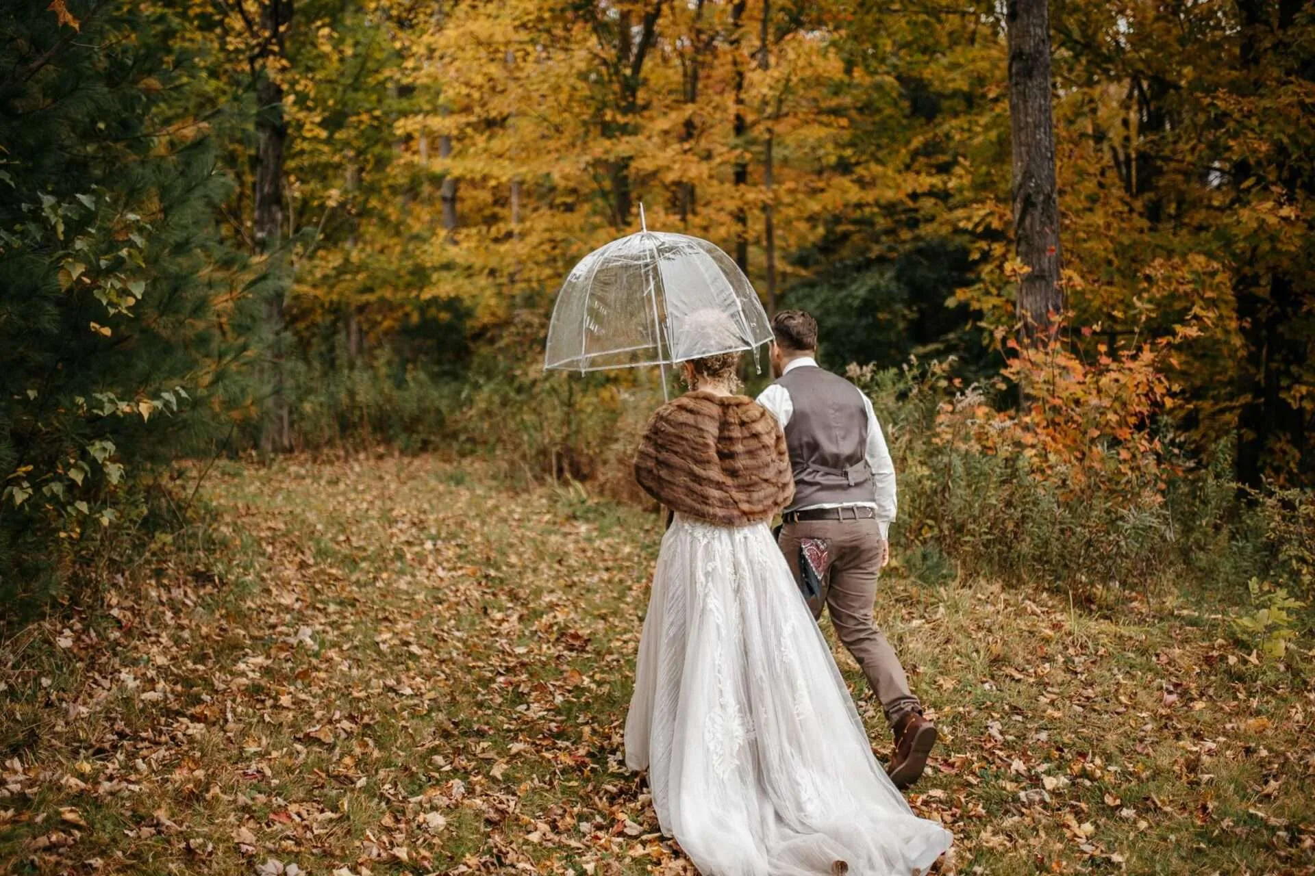 married couple with umbrella in forest on wedding day