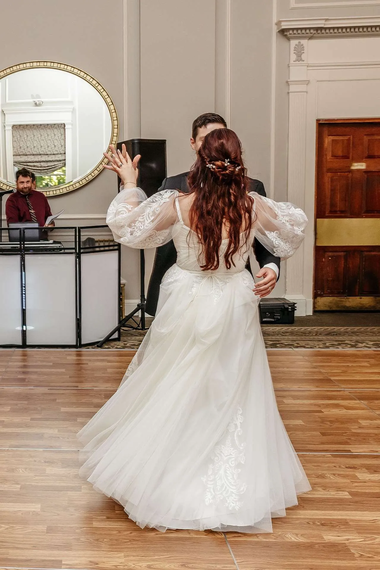 A bride and groom dance at their reception with the DJ in the background at one of boston hotel wedding venues.
