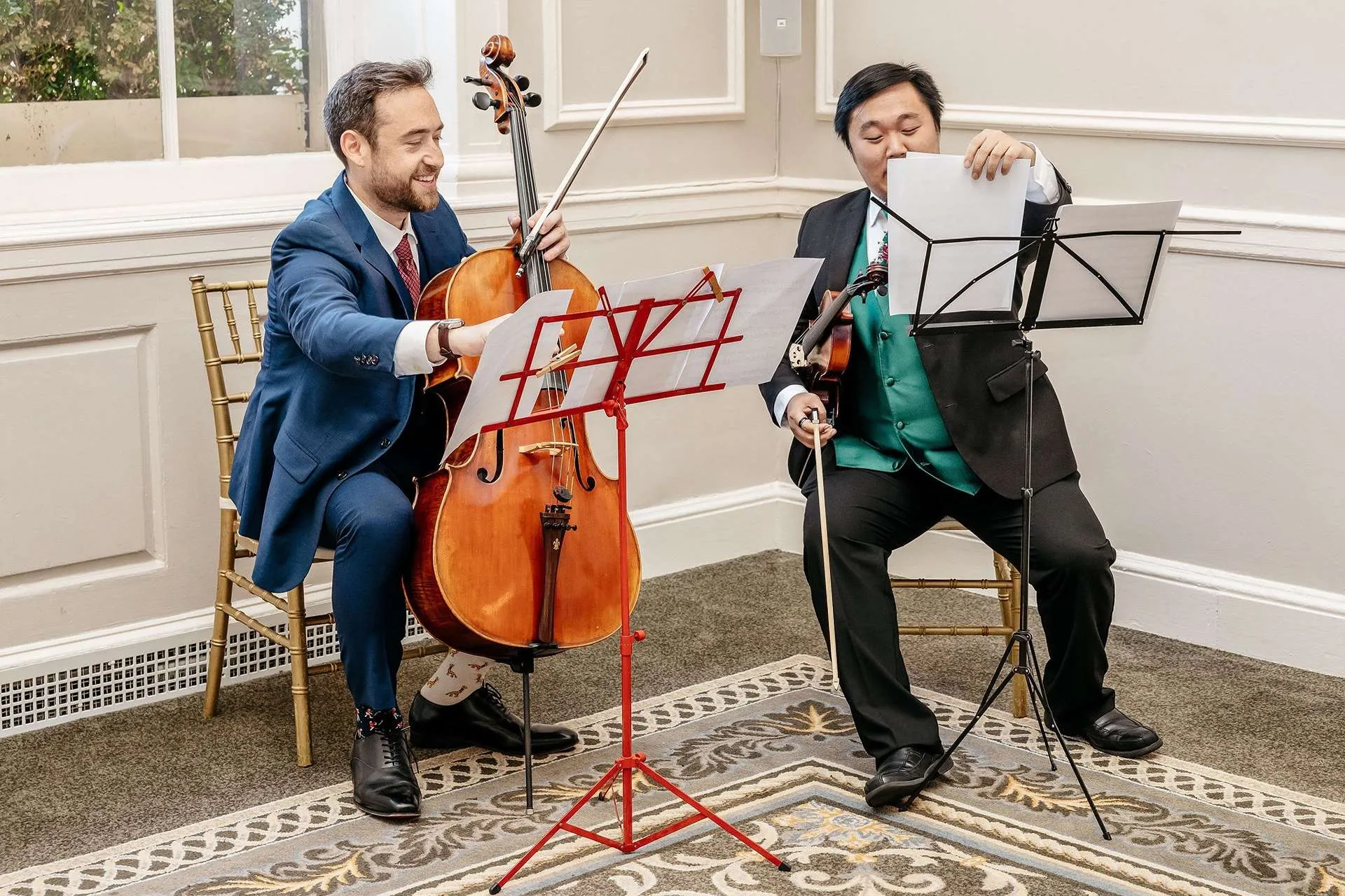 Two musicians with a cello and a violin prepare their music stands for a ceremony at one of the best hotel wedding venues in boston.
