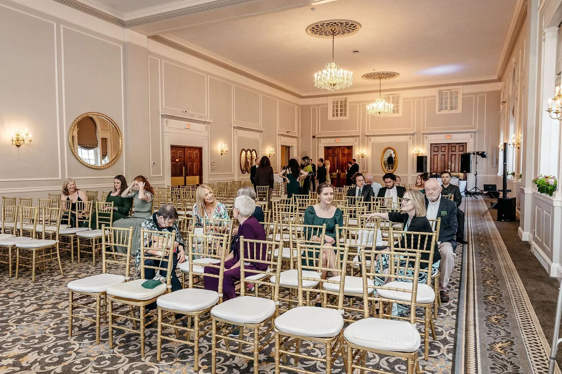 At ​hotel wedding venues in boston families sit in white and gold chairs waiting for the ceremony to begin.