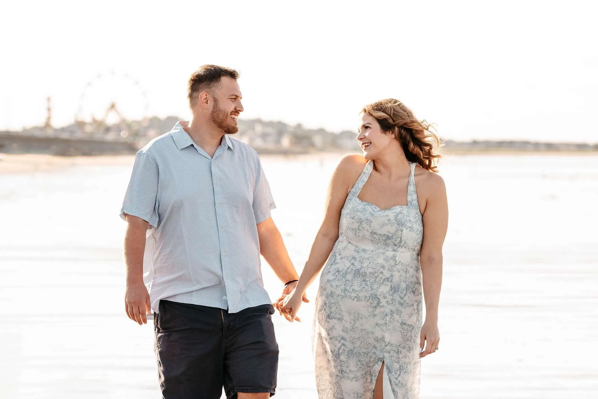 A woman smiles at her fiance while walking on the shore and knowing some cute date ideas in boston.