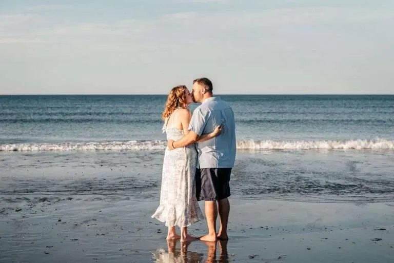 Couple kissing barefoot at the water's edge on a New England beach