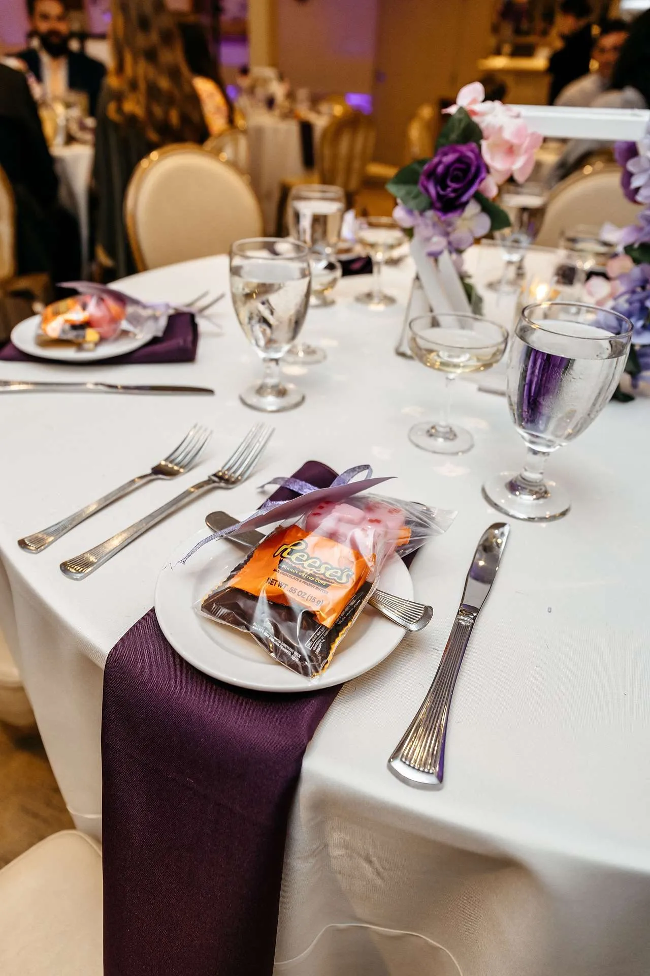 An event photographer in boston takes photos of reception tables with purple napkins and candy bags that await the guests