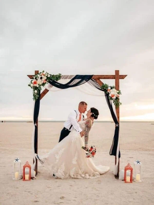 beach wedding arch chatham bars inn cape cod ma A groom dips his bride for a kiss under a wedding arch on the beach at Chatham Bars Inn in Massachusetts.